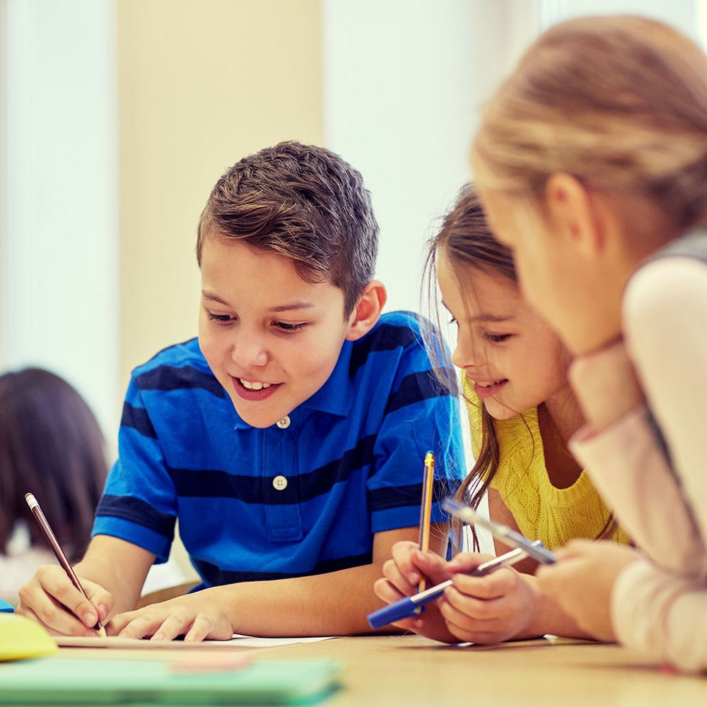 Kinder sitzen gemeinsam an einem Tisch und schreiben